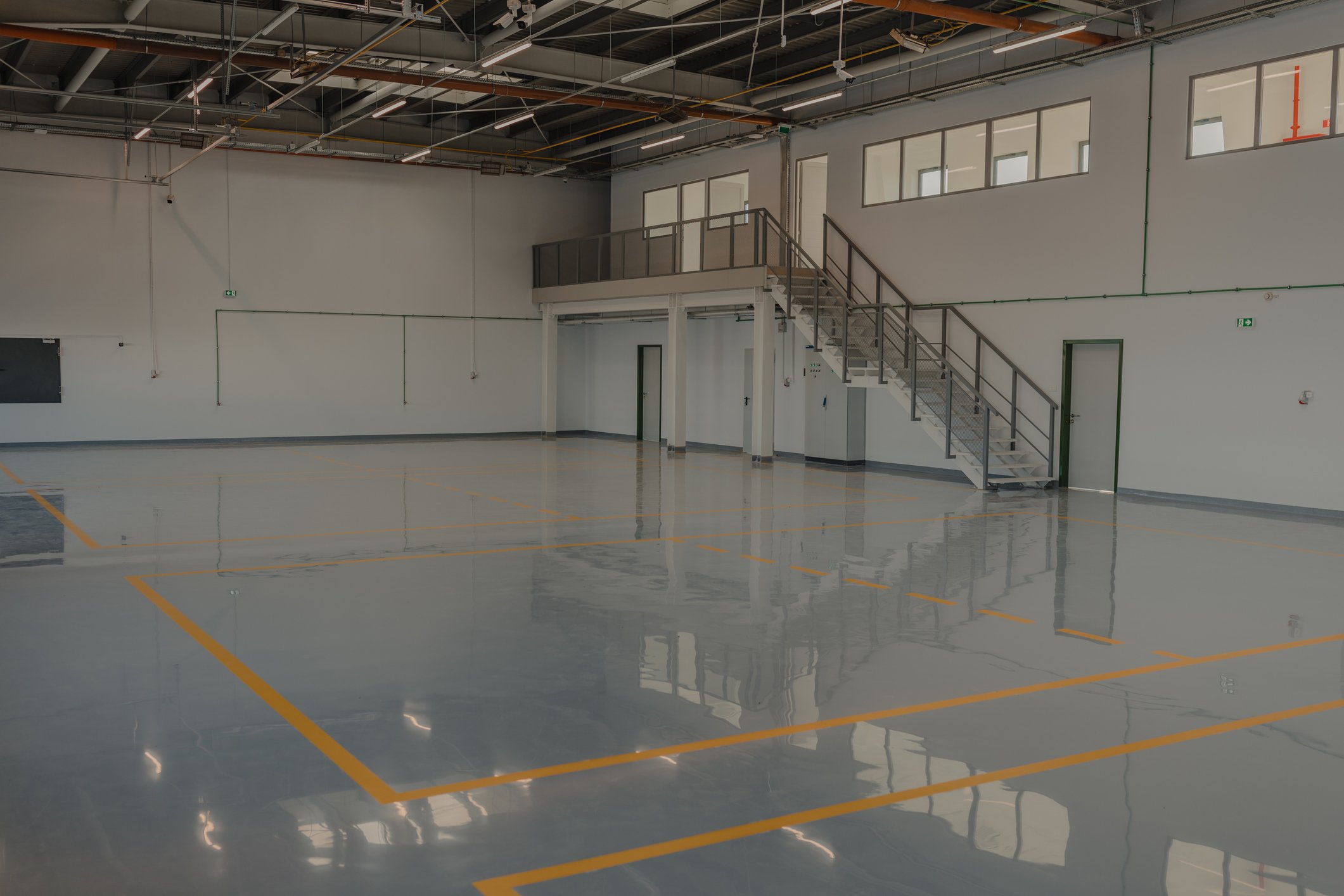 Empty industrial warehouse with polished floor and yellow marking lines