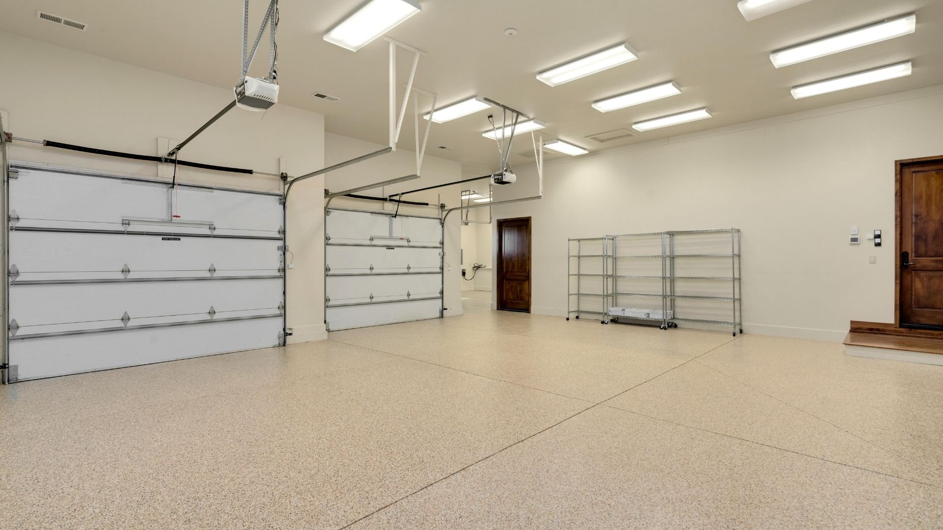 Empty garage with white walls, concrete floor, and two large garage doors