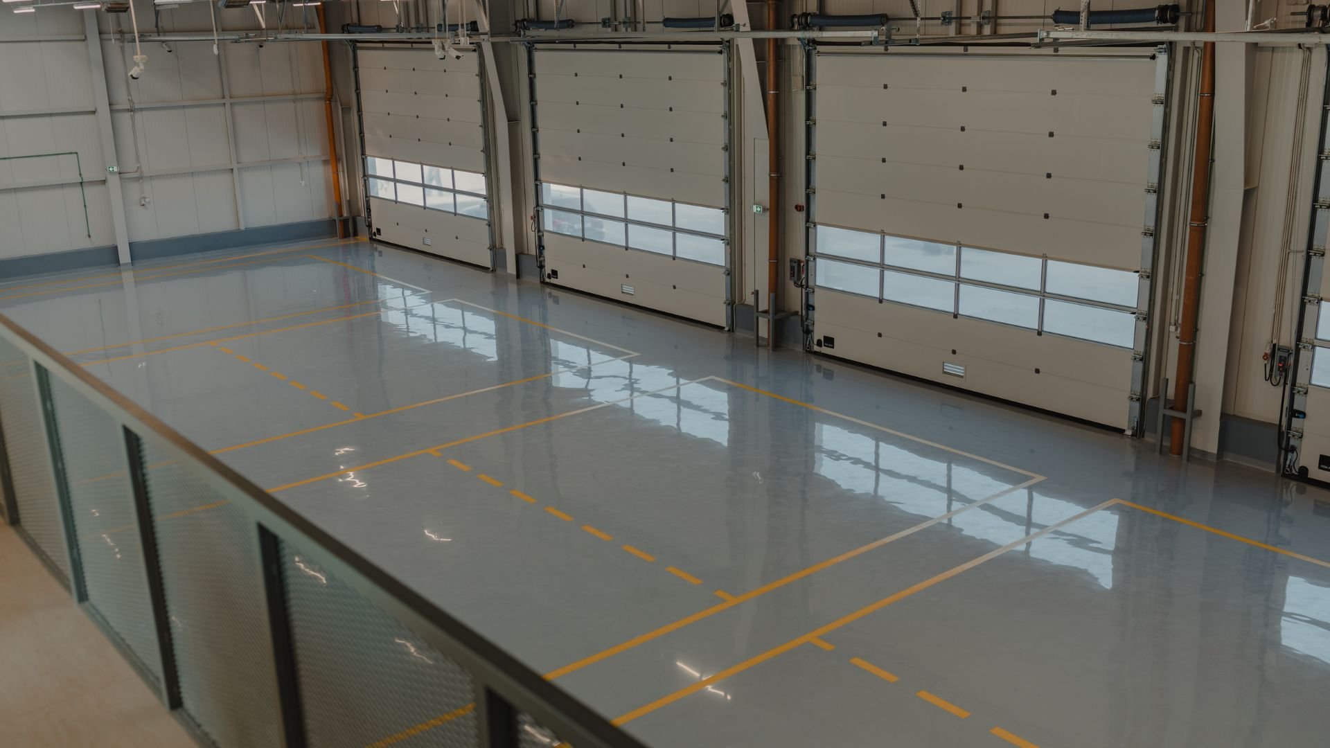 Empty industrial warehouse with large garage doors and glossy floor
